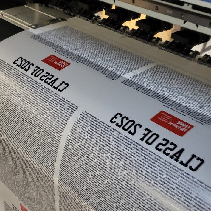 Large printing machine with a roll of paper featuring text and logos.