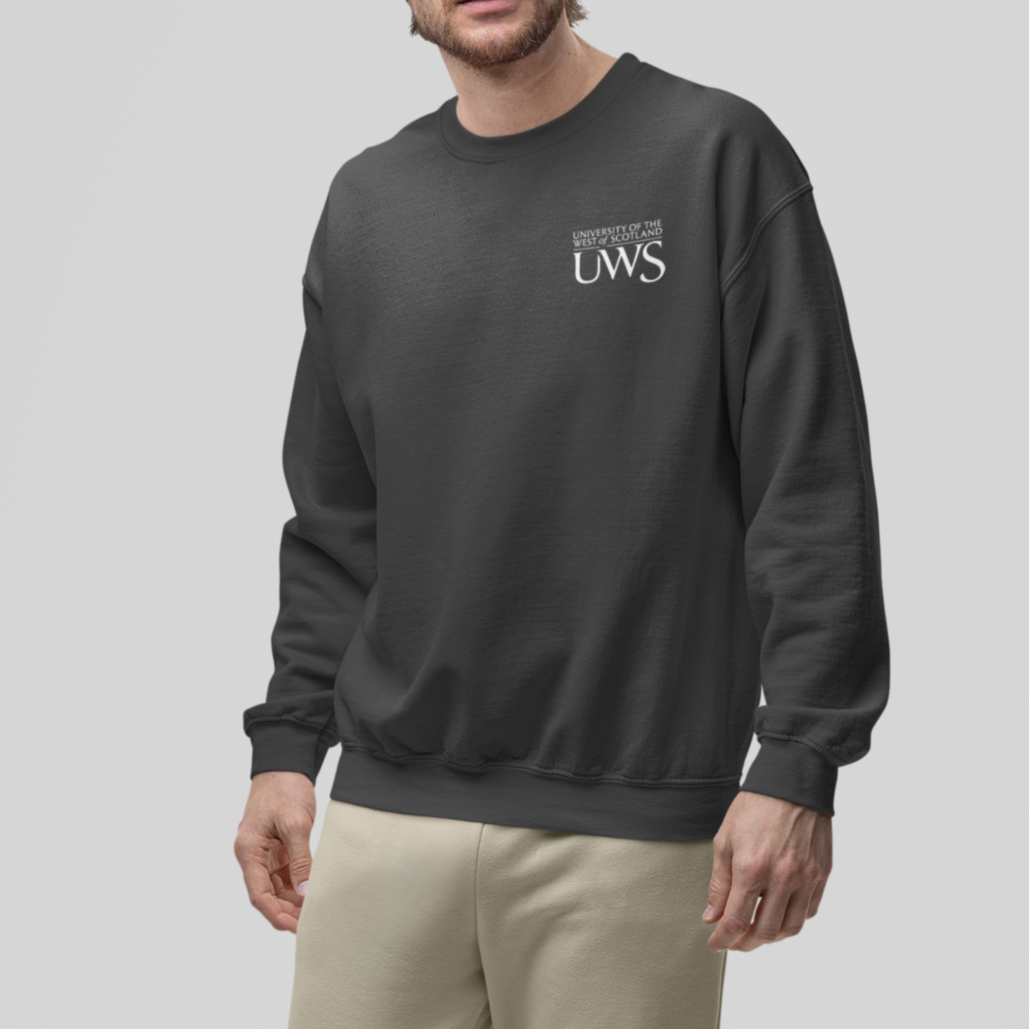 Man wearing a dark gray sweatshirt and beige pants on a light gray background