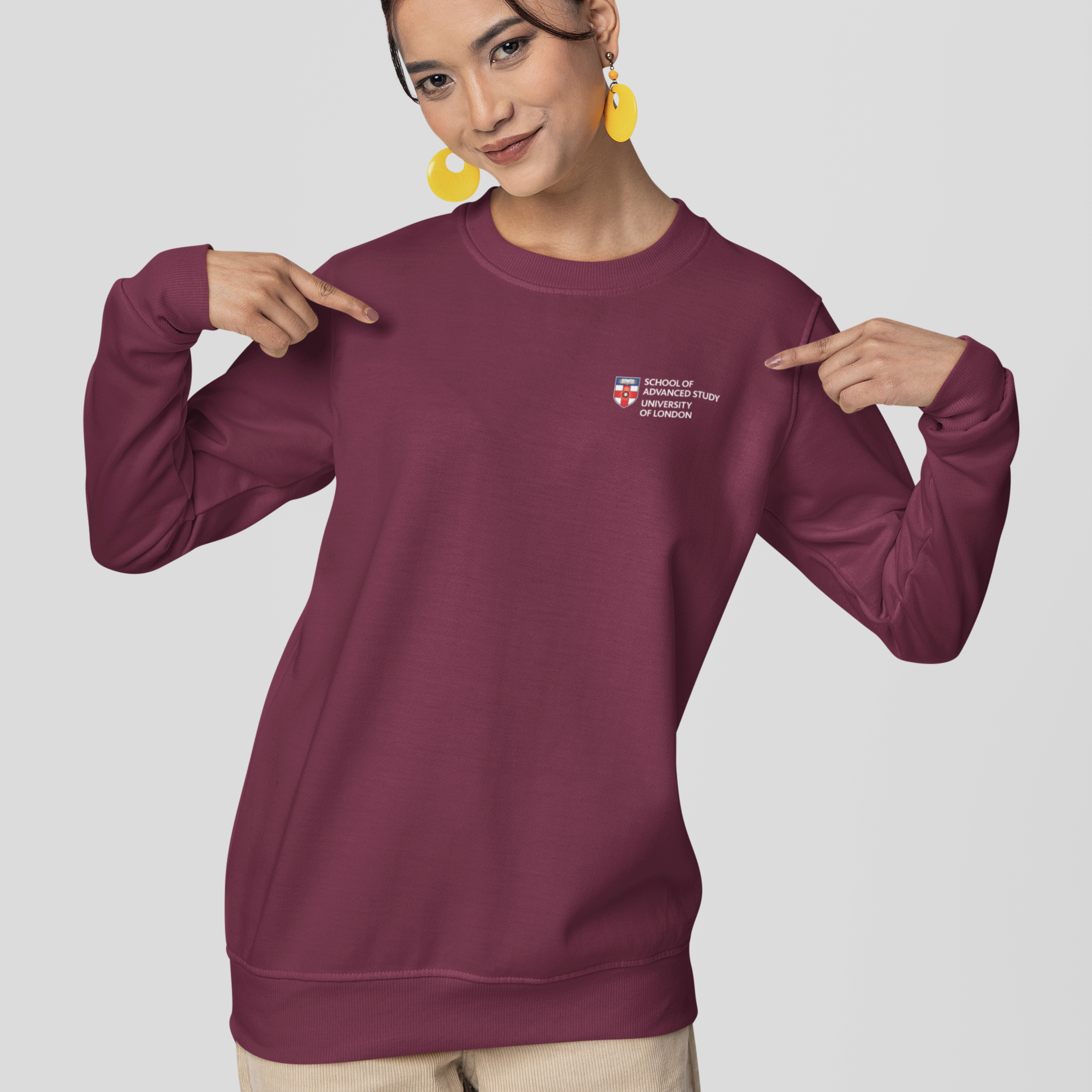 Woman pointing to a maroon sweatshirt with a logo on a light gray background